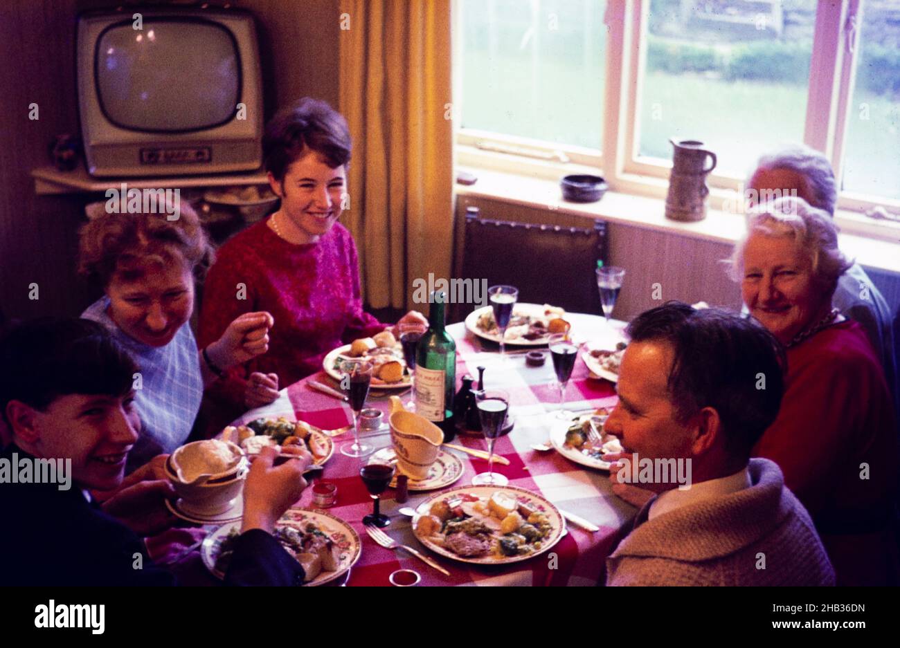 Traditional family Christmas meal all sitting around table eating and drinking, c 1960, England, UK Stock Photo