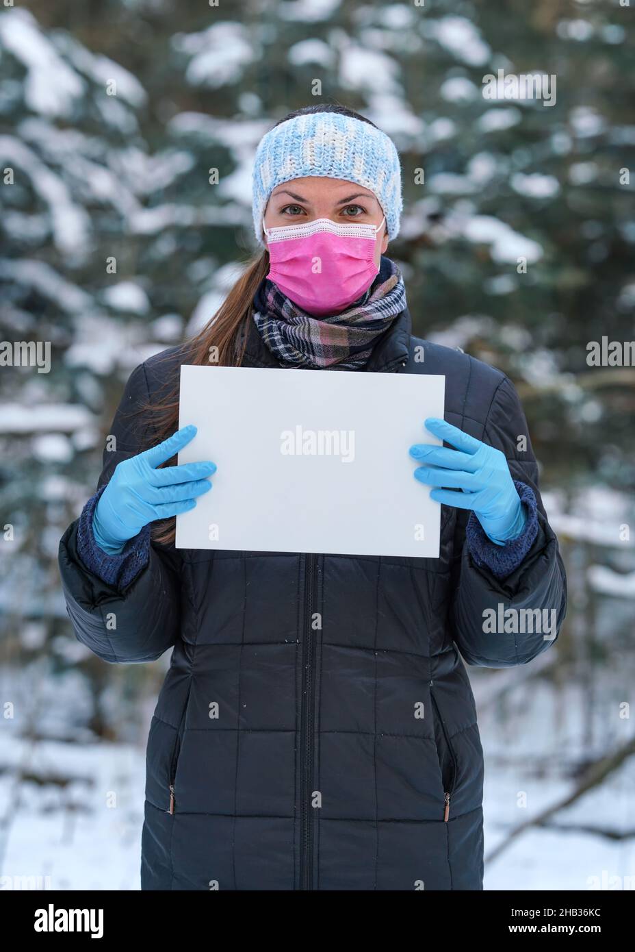 Young woman in winter jacket with pink disposable single use face virus