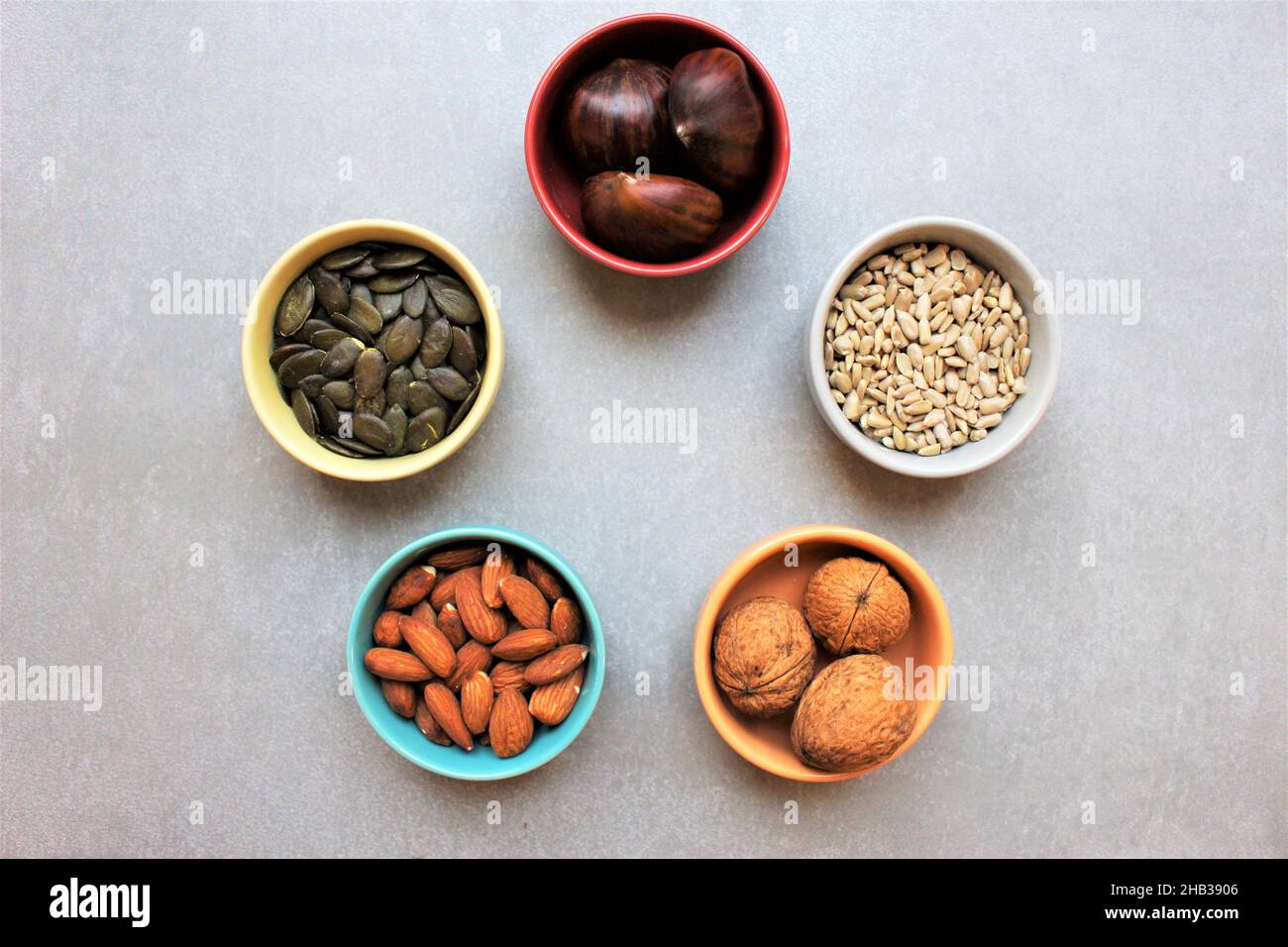 5 ceramic bowls containing whole nuts and seeds. Concept for health