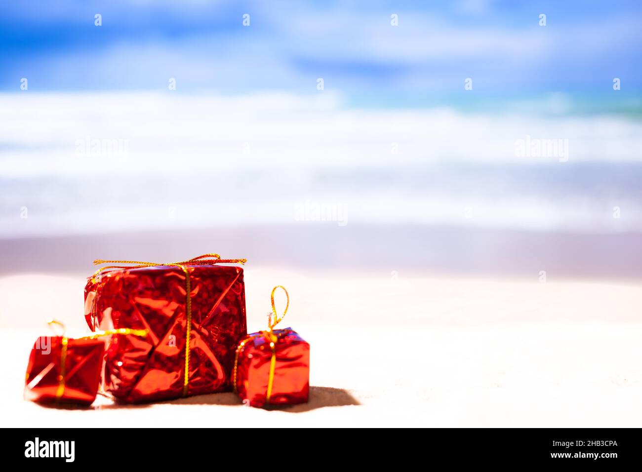 Three red New Year's gifts on the beach against the background of osean, copy space. New year on the beach Stock Photo