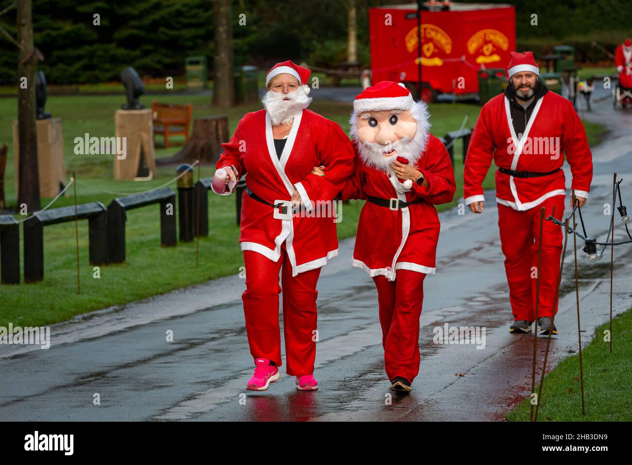 People running in a Santa Dash, one wearing a large face mask Stock Photo