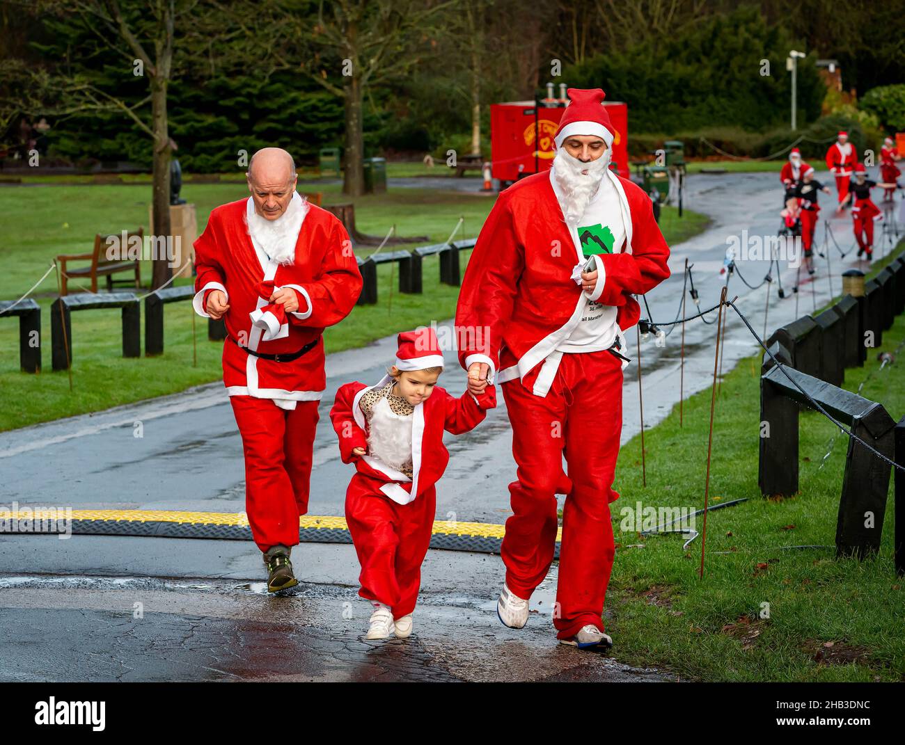 Man and daughter hold hands whilst running in a Santa Dash Stock Photo