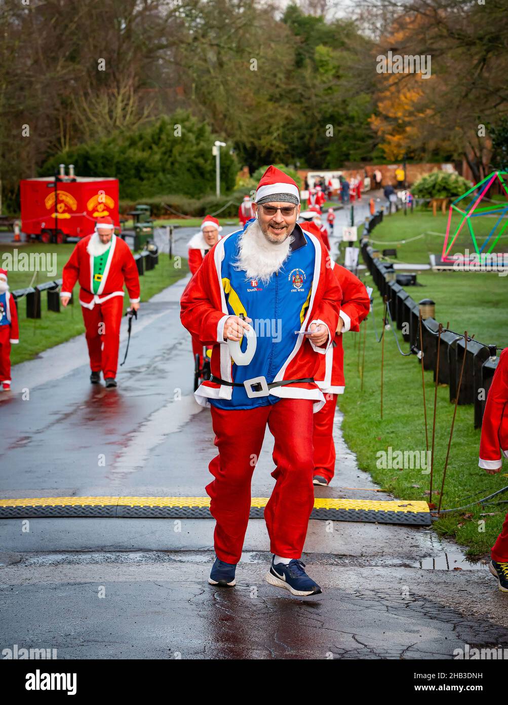Man with own beard, ear pods and headband running in a Santa Dash Stock Photo