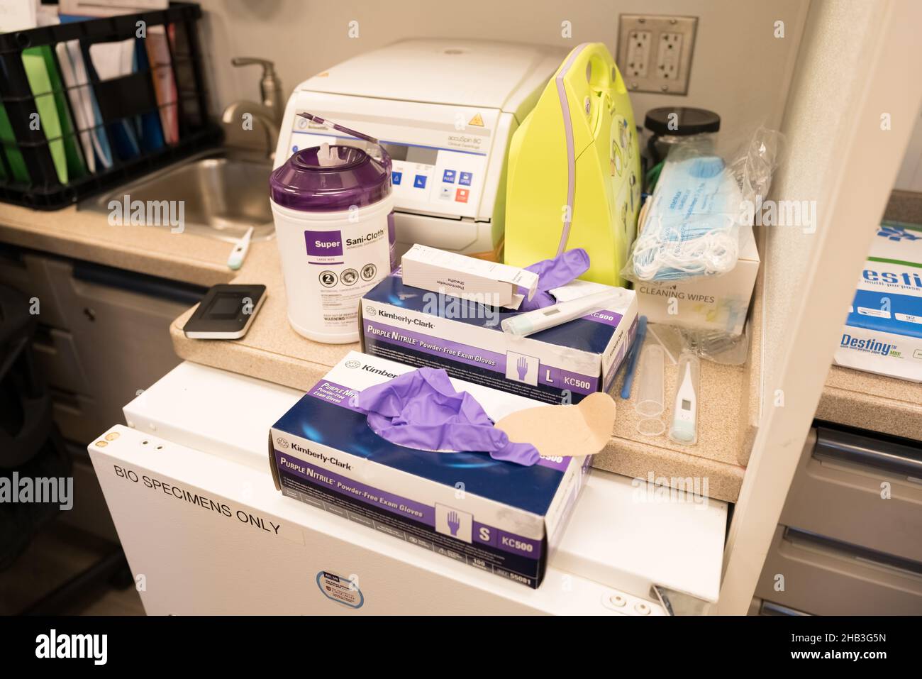 Laboratory space showing boxes of purple Kimberly-Clark disposable gloves sitting on top of a biological specimen refrigerator. Stock Photo