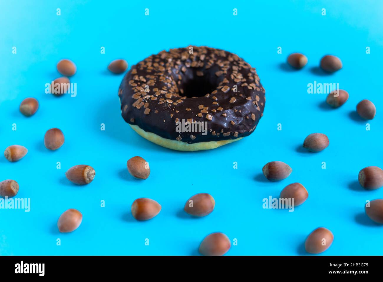Donut with hazelnuts on a blue background, close up Stock Photo