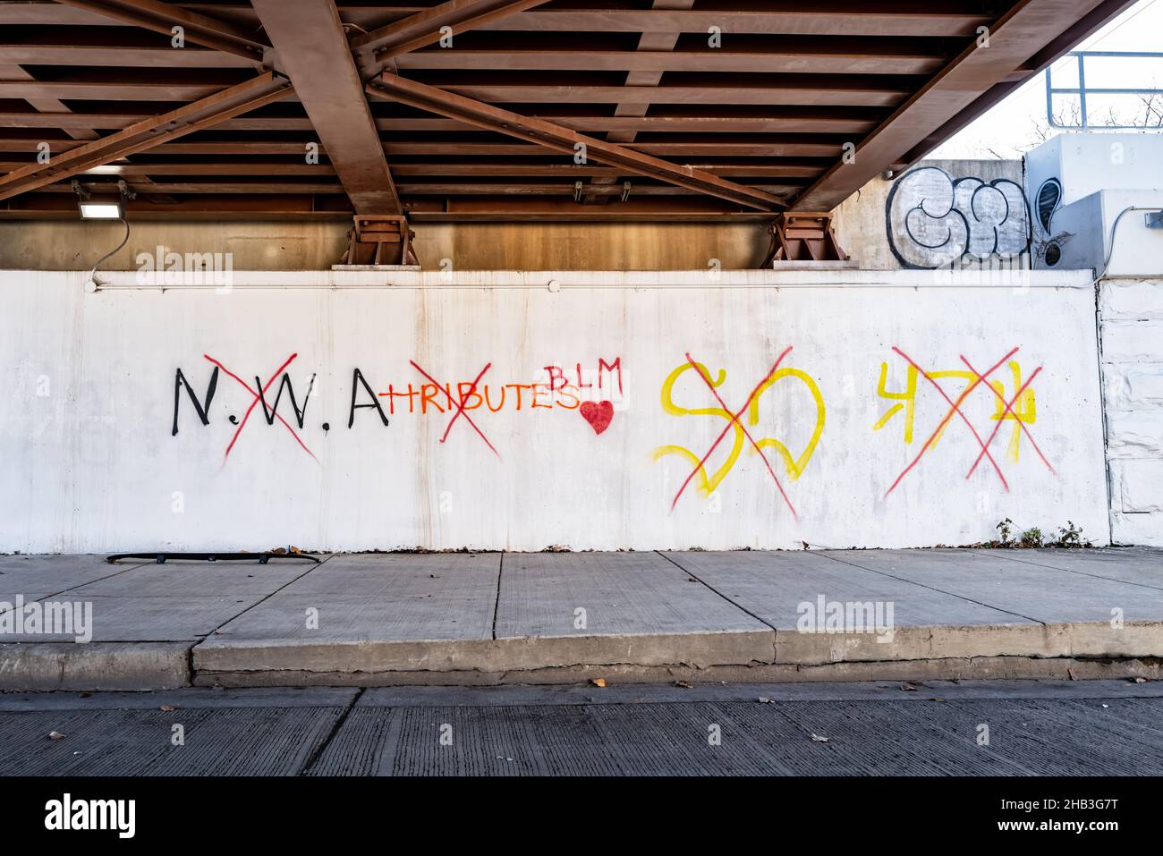White wall with various graffiti where the original graffiti of NWA and some graffiti tags has been crossed out and BLM with a heart has been written in instead. Stock Photo