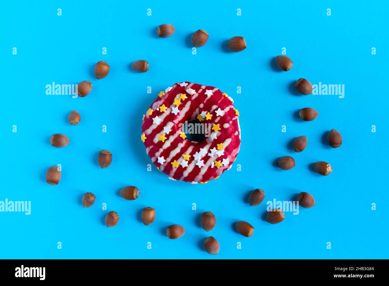 Donut with hazelnuts on a blue background, close up Stock Photo