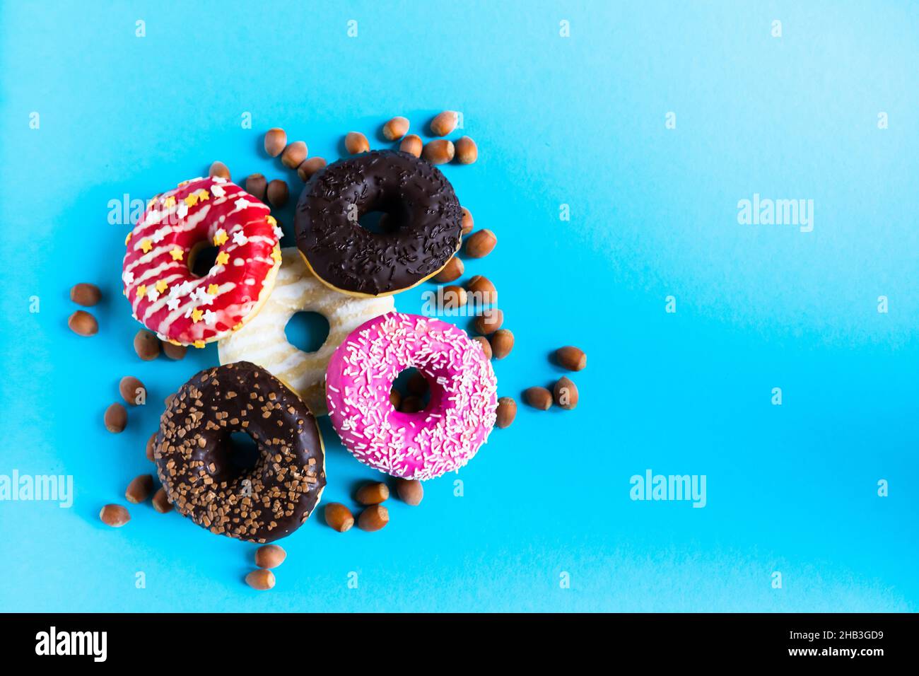 Donut with hazelnuts on a blue background, close up Stock Photo