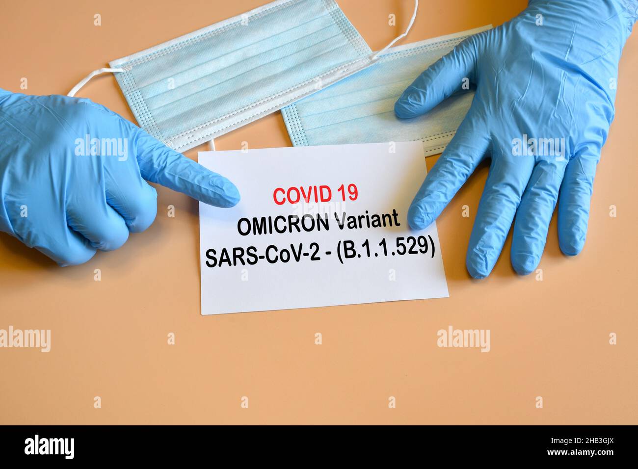 Covid-19 new Omicron variant. Doctor hand with blue glove indicate written 'Covid-19 variant Omicron' on white paper. Stock Photo