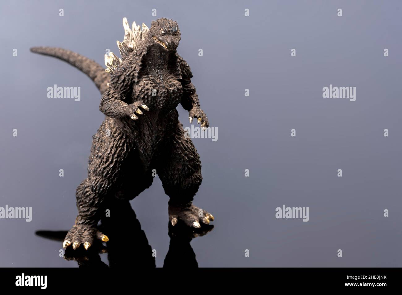 A black ugly looking lizard toy. Legendary Asian monster. A giant figure mascot. Plastic creature in detail on reflecting surface. Cultural object. Stock Photo