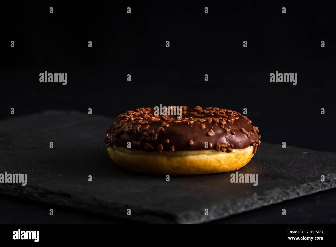 Closeup of a delicious chocolate glazed donut isolated on a black ...