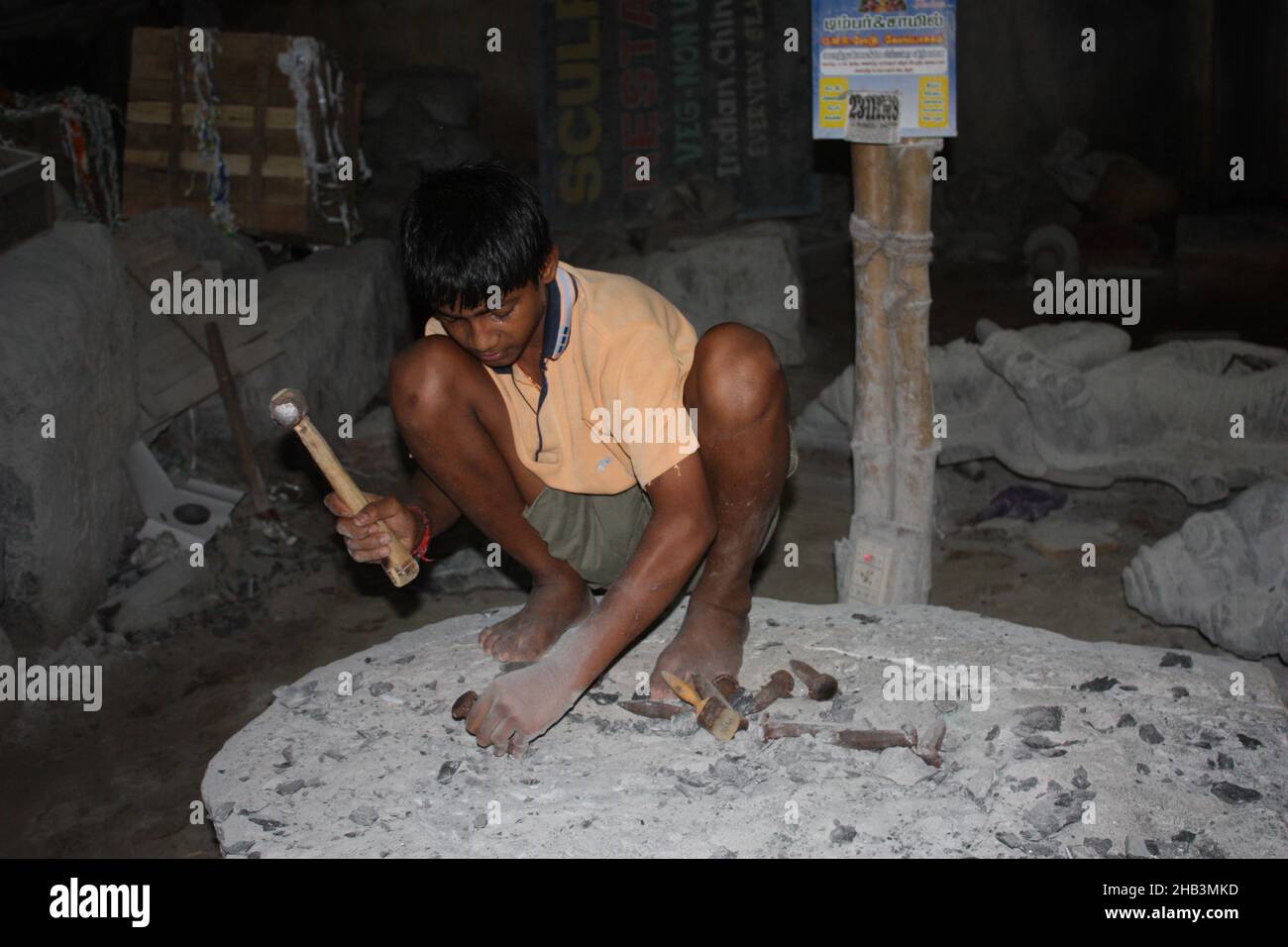 Inside the sculptor shop there was a child working hard in the dust, in the dark, a child exploitation so common in India, near Mamallapuran. Stock Photo