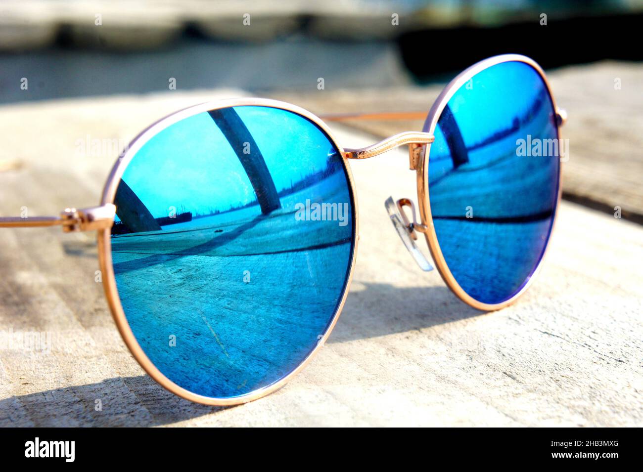 fashionable mirror glasses with blue glasses on the sun lie on a wooden floor rest trip reflected in glasses Stock Photo