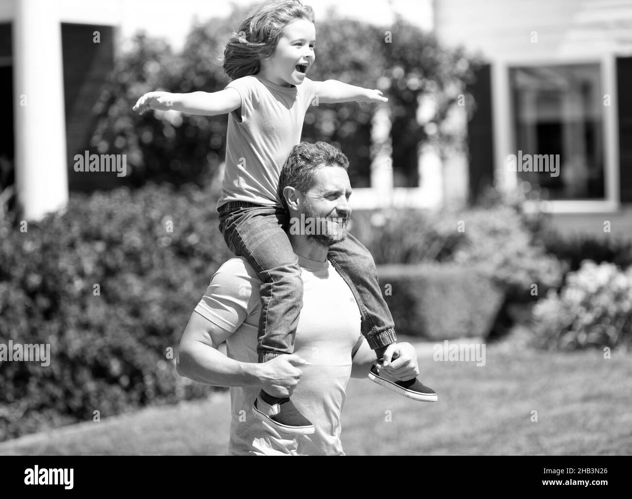 Happy man carry son kid sitting on fathers shoulders summer outdoors, piggy-back Stock Photo