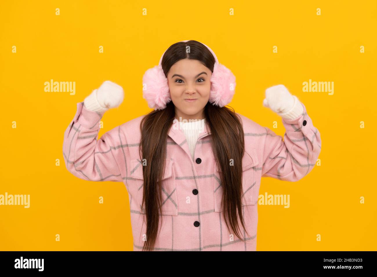 express emotion. winter fashion. angry kid in fur earmuffs showing fists. Stock Photo