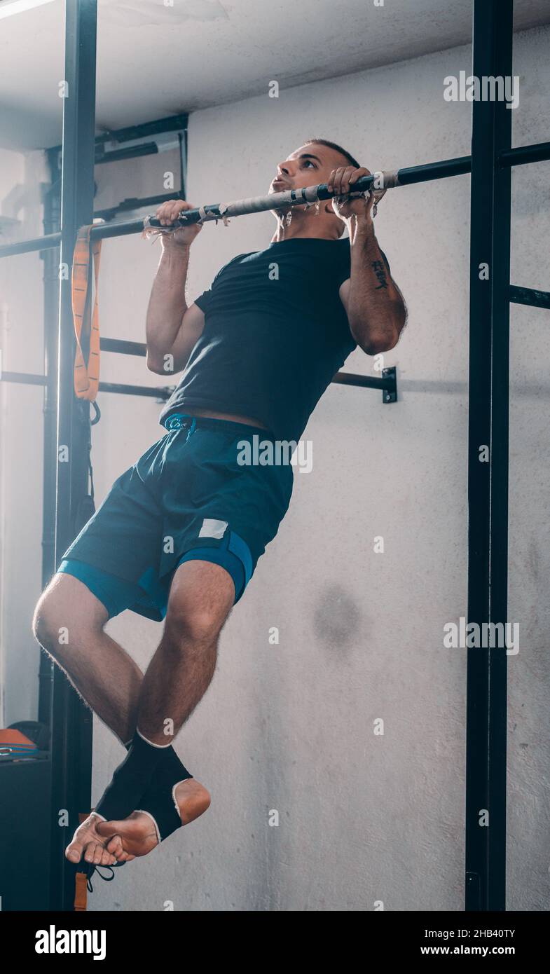 Crossfit man doing pull-ups on chin-up bar during workout outdoors Stock Photo