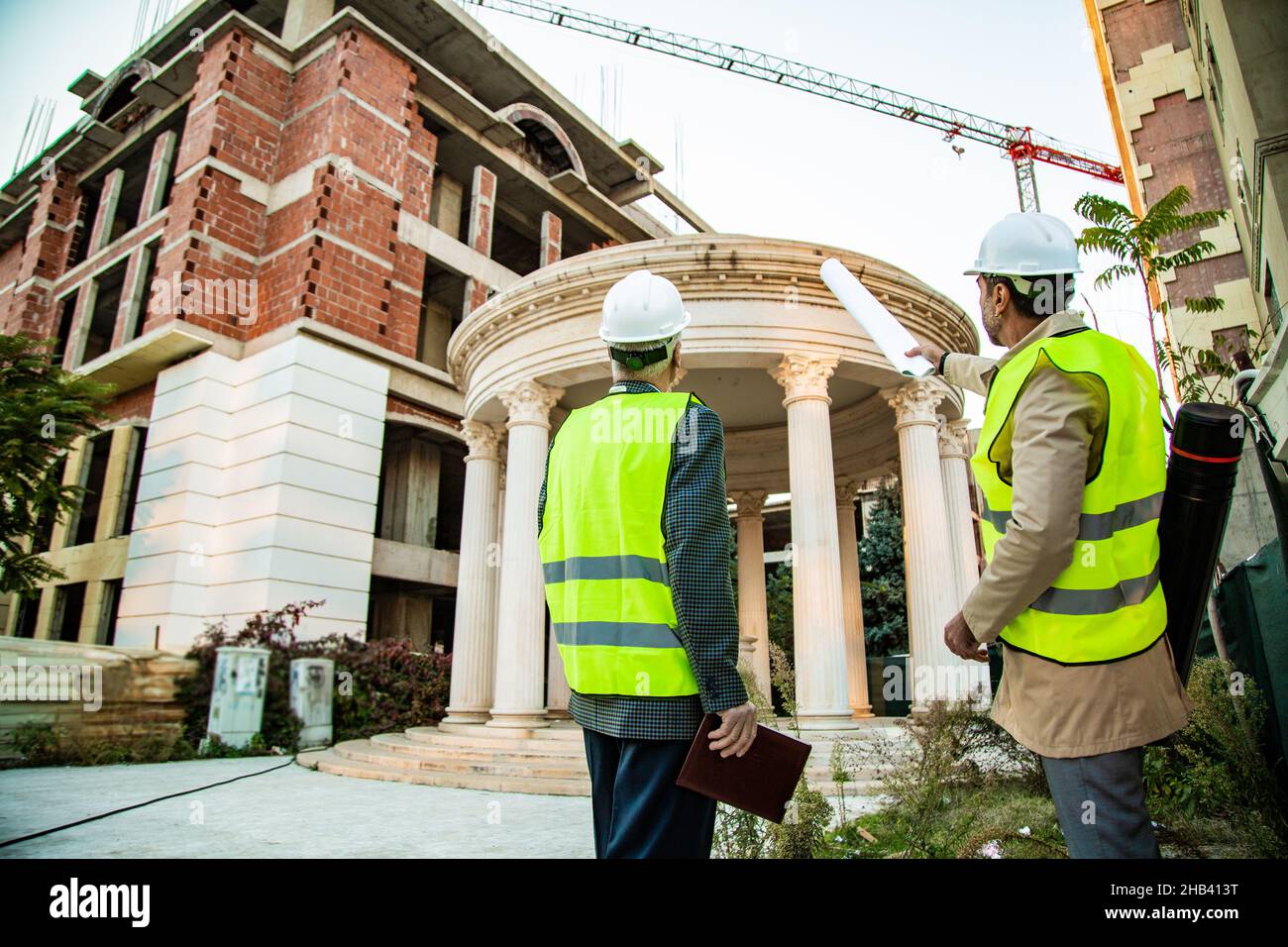 Two construction workers are looking at the construction area while talking Stock Photo
