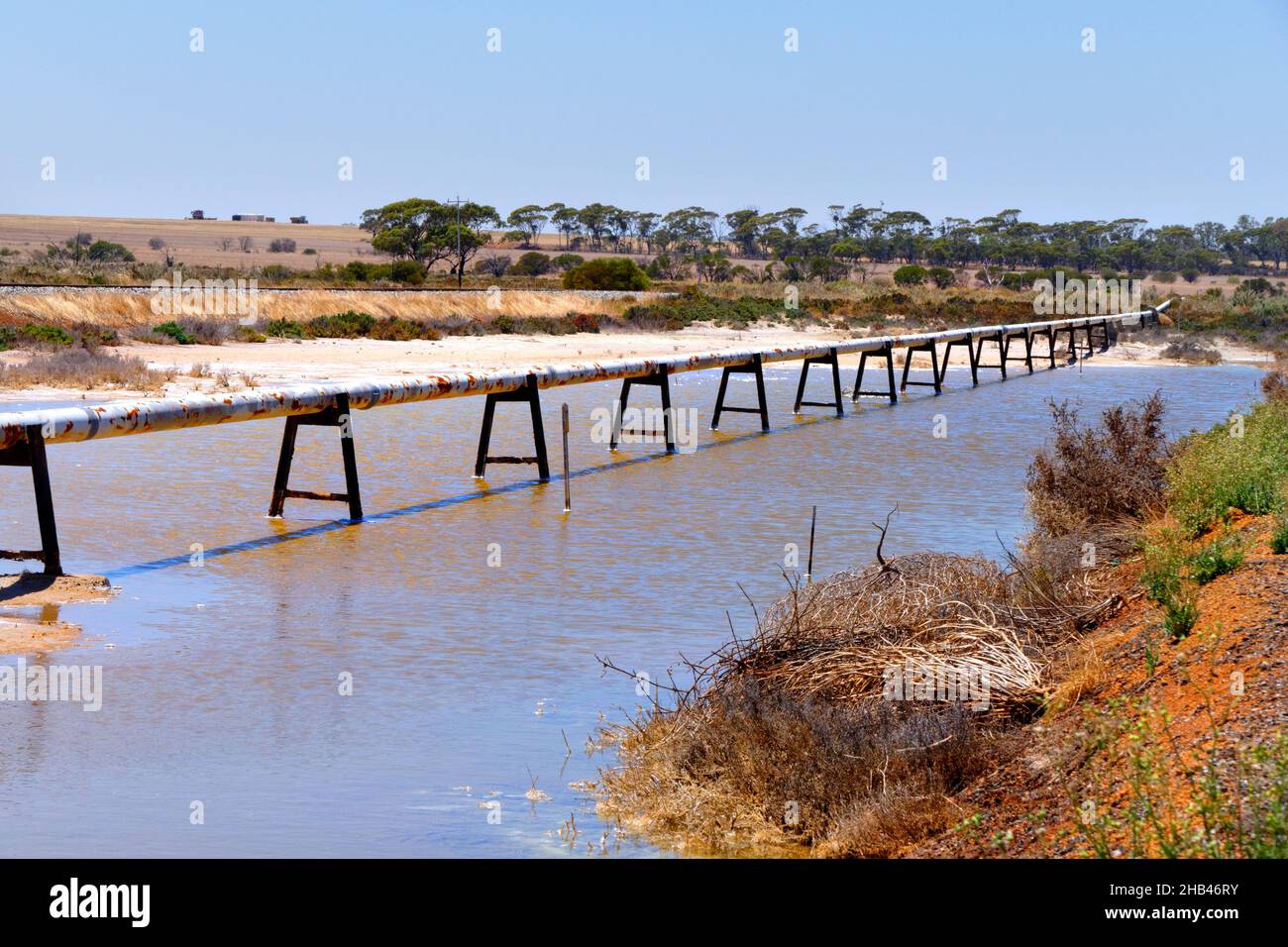 Cross country water pipe on stands crossing salt lake, Wongan Hills, Western Australia Stock Photo