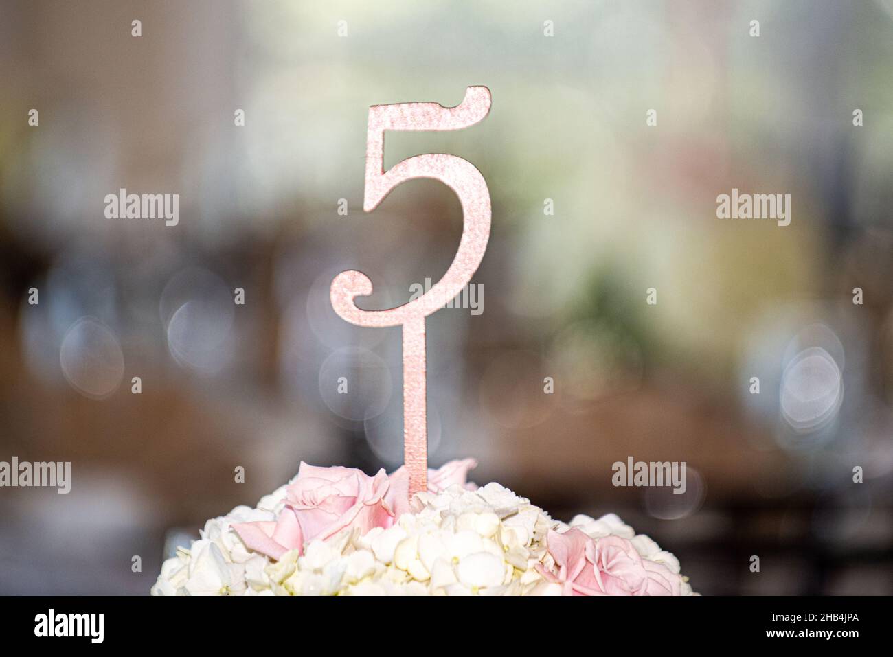 Pink number five guest place indicator sign in flowers at elegant wedding reception table Stock Photo