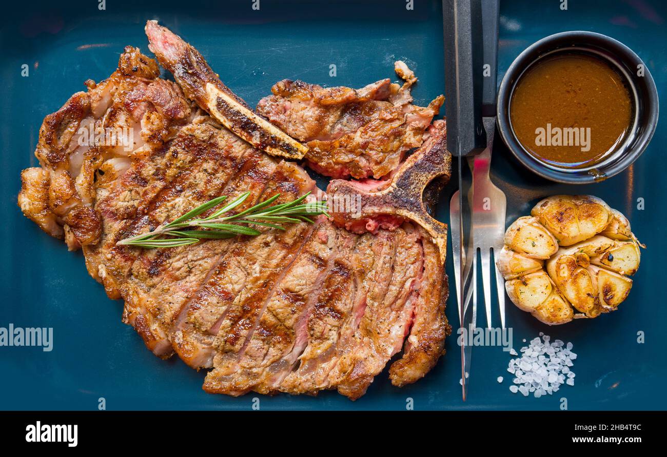 Tbone steak with Garlic Herb butter served on dark blue plate Stock