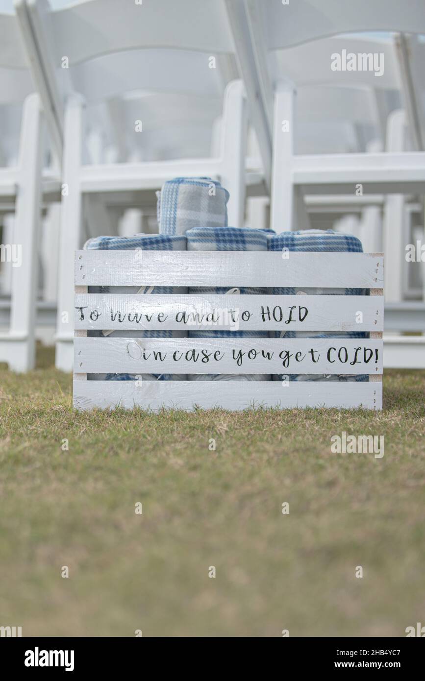 White slated crate at wedding with 'To have and to hold in case you get cold' text containing rolled up guest blankets Stock Photo