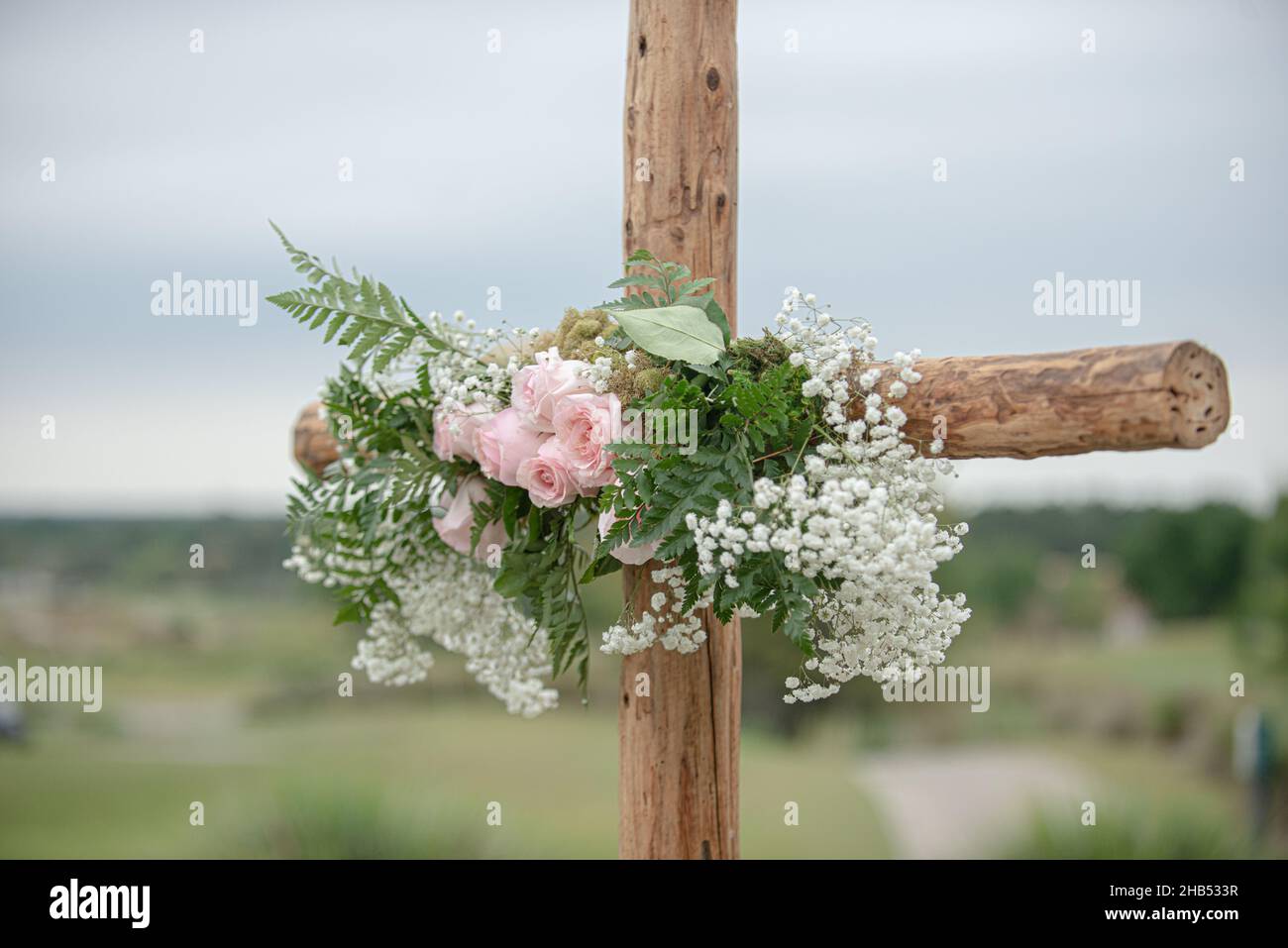 Wooden cross wedding altar with pink roses for outdoor wedding ceremony Stock Photo