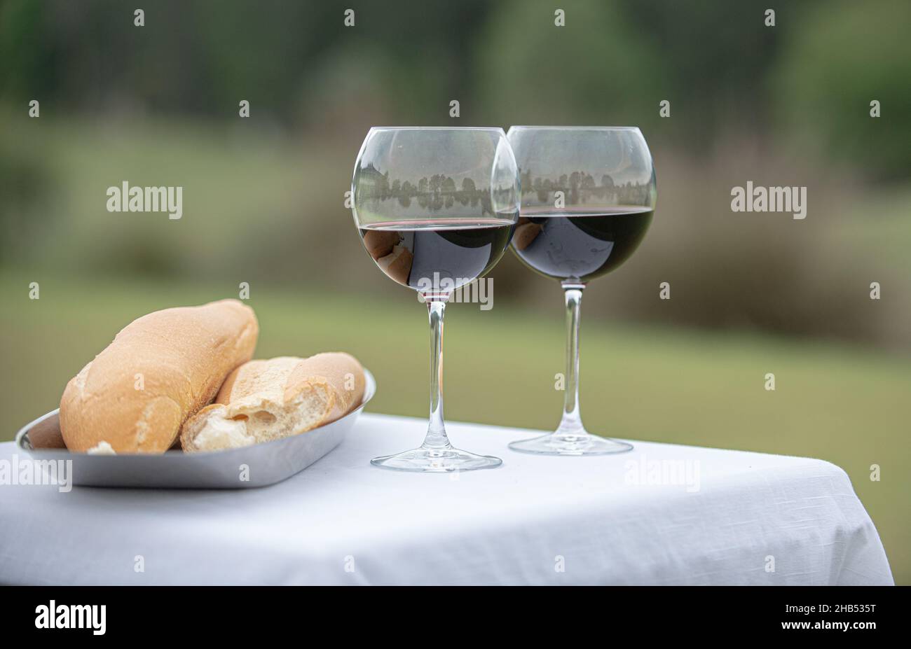 Breaking bread wedding ceremony filled wine glasses and bread outdoors
