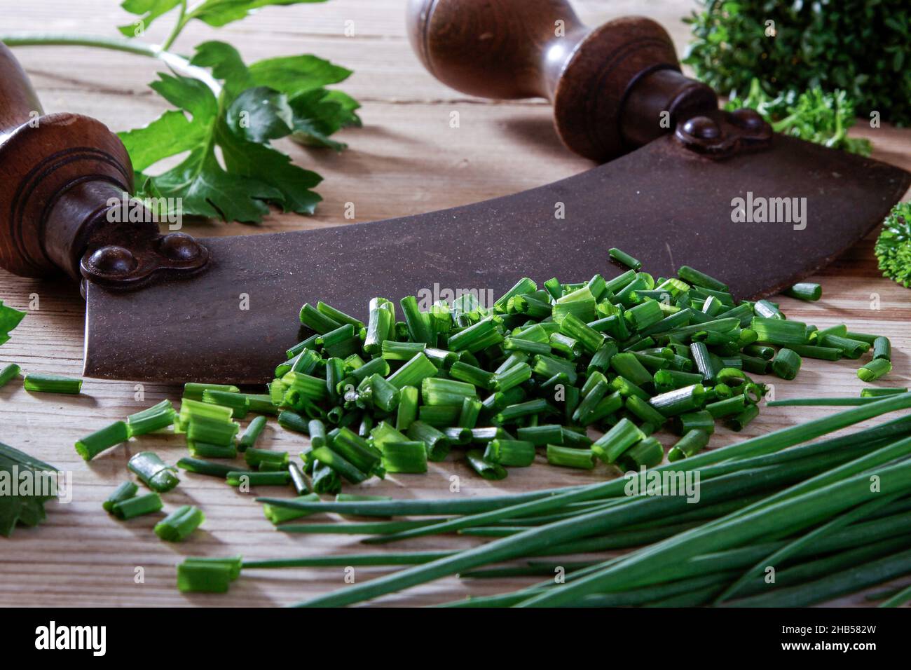 old chopping knife with leek and parsley on a wooden background Stock Photo