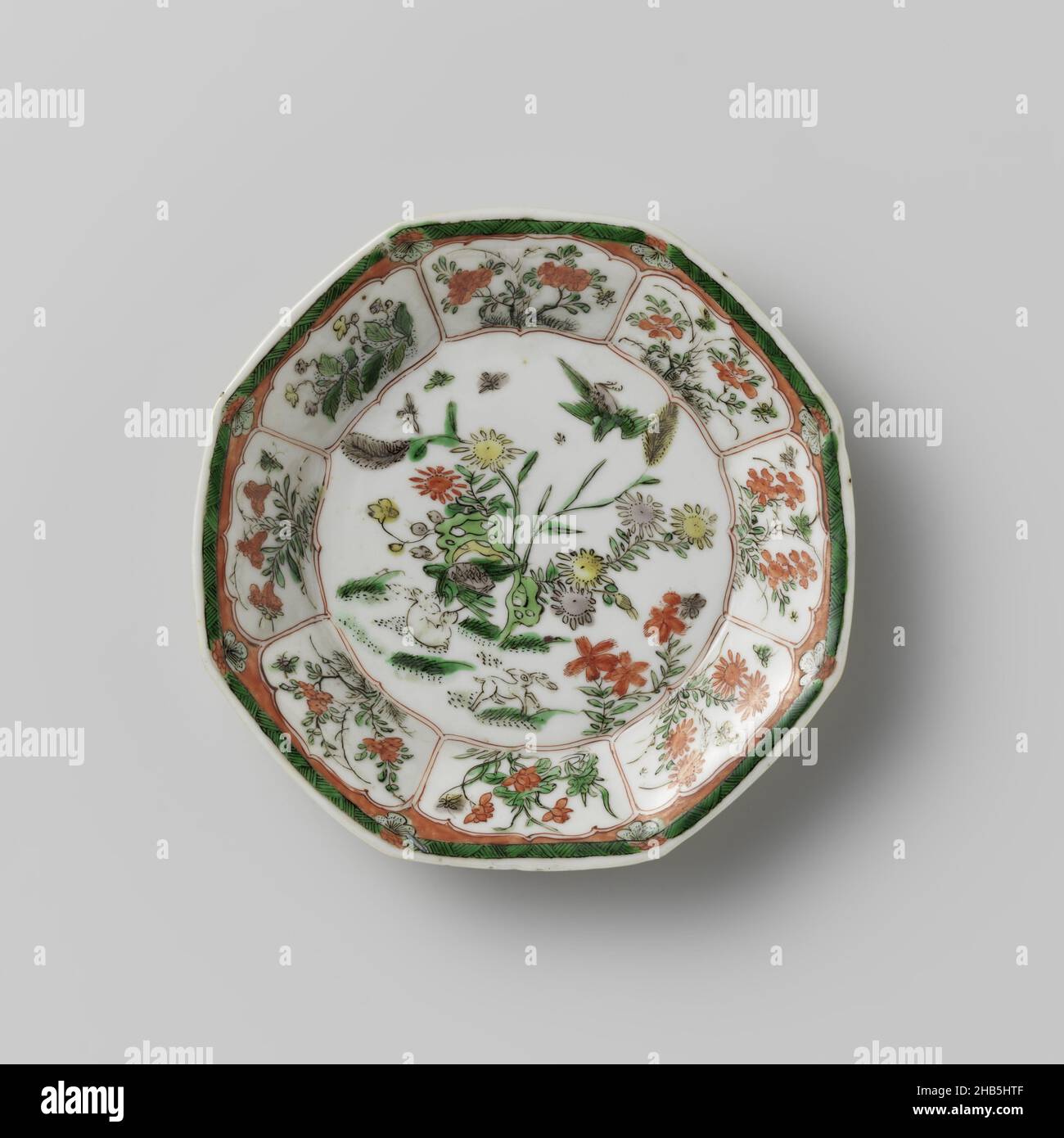 Octagonal saucer with light brown, animals and flower sprays, Octagonal saucer of porcelain, partially covered with café-au-lait, painted in underglaze blue and on the glaze red, green, yellow, eggplant and black. On the flat, two hares and two birds near a rock with flowering plants; the wall with flower branches and butterflies in a box decoration; the rim with zigzag work alternating with flowers. The exterior is covered with a café-au-lait glaze with flower branches. Marked on the underside with a character in a double circle. Famille verte with monochrome brown glaze., anonymous, China, c Stock Photo