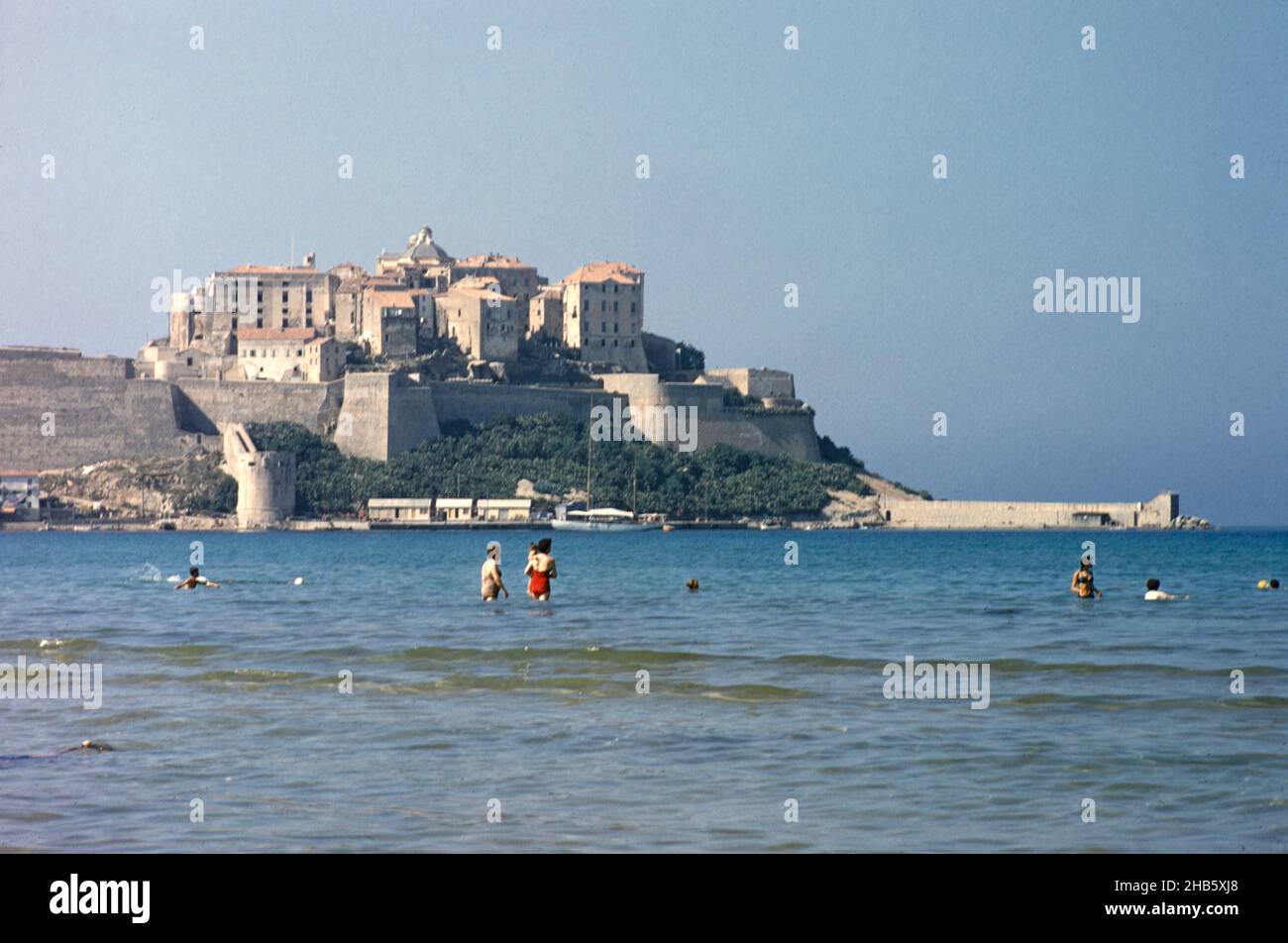 Calvi, Corsica, France in late 1950s people swimming with town citadel in background Stock Photo