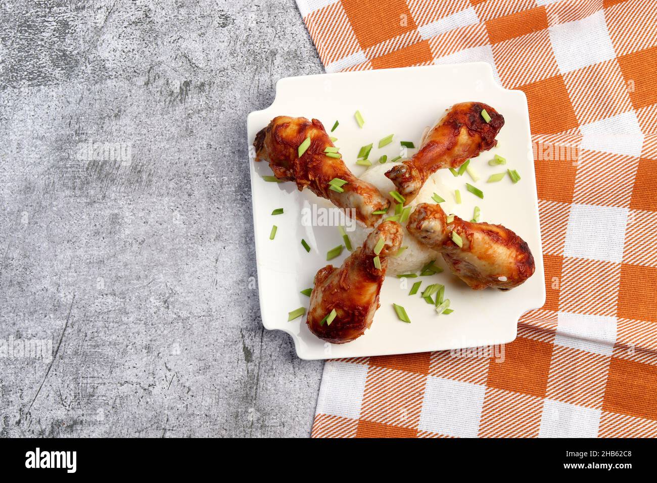 Oven baked chicken drumsticks with rice on a white square plate on a