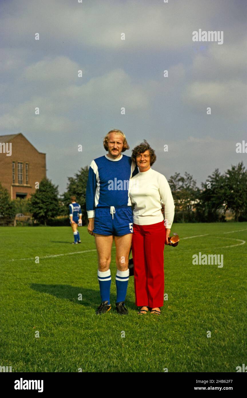 Full length portrait on man in football sports kit standing next to his mother, UK 1975 Stock Photo