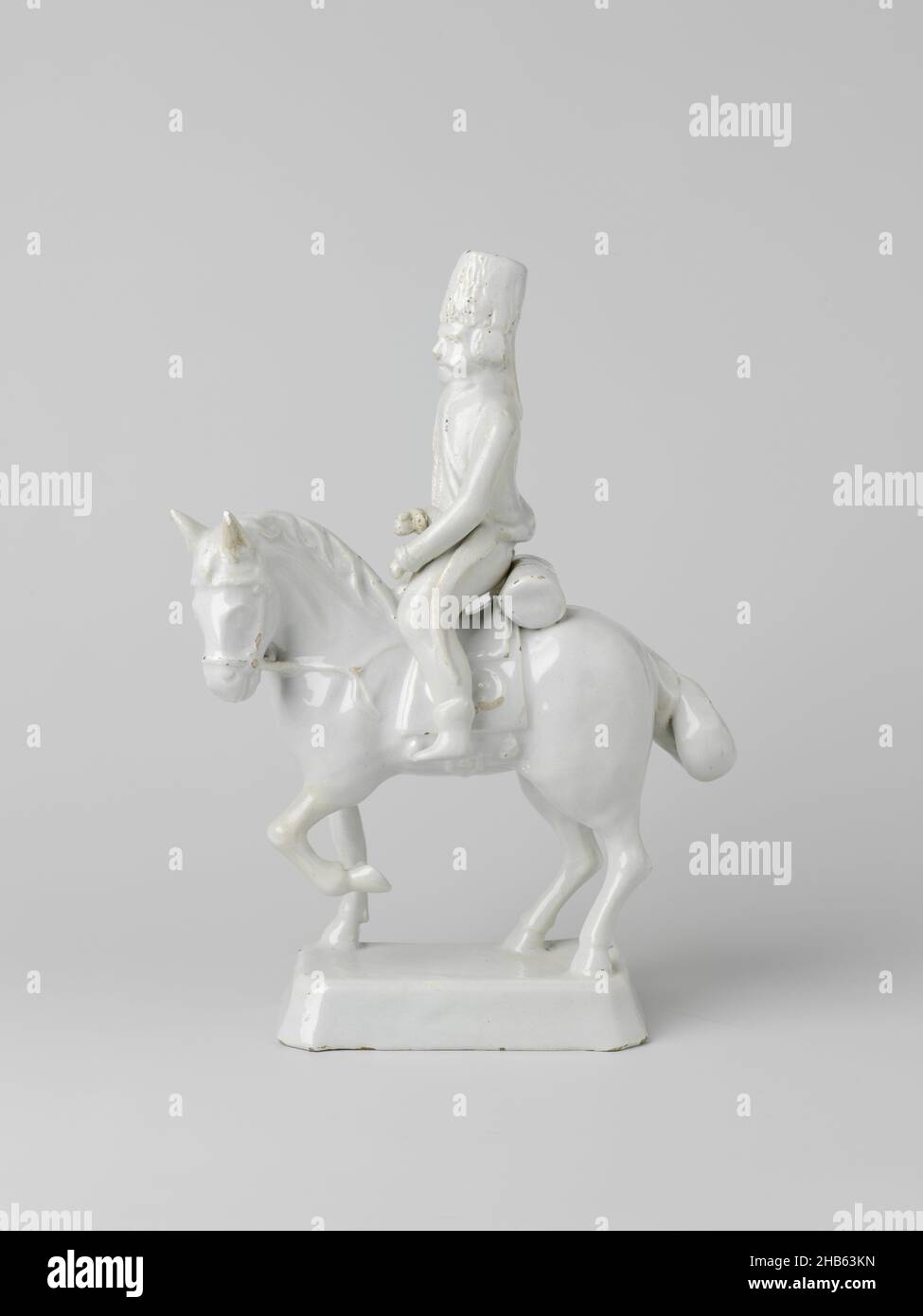 Horse with rider, Horseman of undecorated faience. The horse stands on a rectangular base and the rider sits loose on it. The rider wears a bereb hat and a German uniform from the second half of the 18th century. The horse has its left foreleg raised. The rider is accompanied by an identical example, anonymous, Delft, c. 1700 - c. 1800, earthenware, tin glaze, height 32 cm Stock Photo