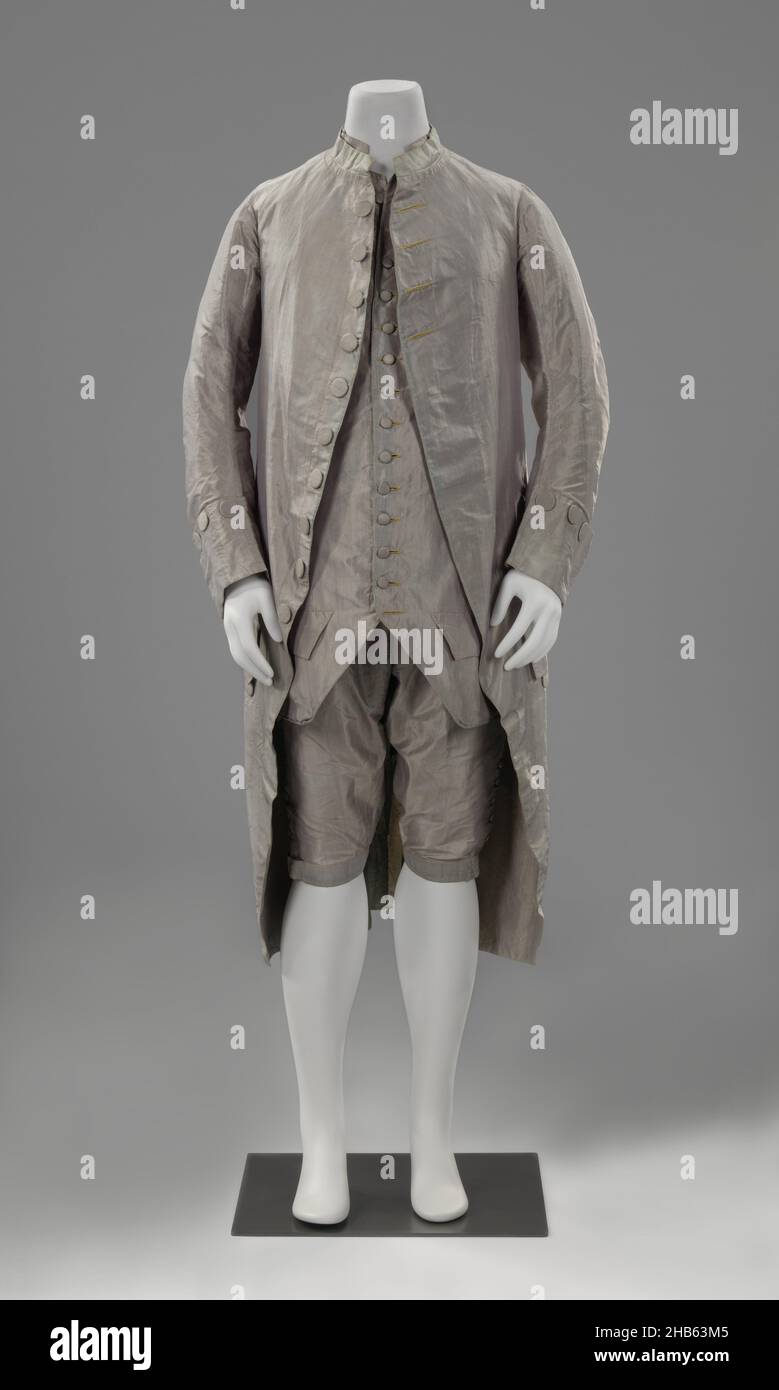 Suit: coat, breeches and waistcoat, Men's costume of mauve-gray changeant taffeta, consisting of a coat or frak, a vest or kamizool and knee breeches, Men's costume of mauve-gray changeant taffeta, consisting of a coat or frak (a), a vest or kamizool(b) and knee breeches (c). Model: (a) round cut fronts, one back seam and two single side pleats. Half-high standing collar, close-fitting sleeves with small cuff, fabric buttons, three yellow mock buttonholes. The fronts are lined with the same taffeta; (b) shorter than the jacket, angularly cut fronts, sleeveless, standing collar and two pockets Stock Photo