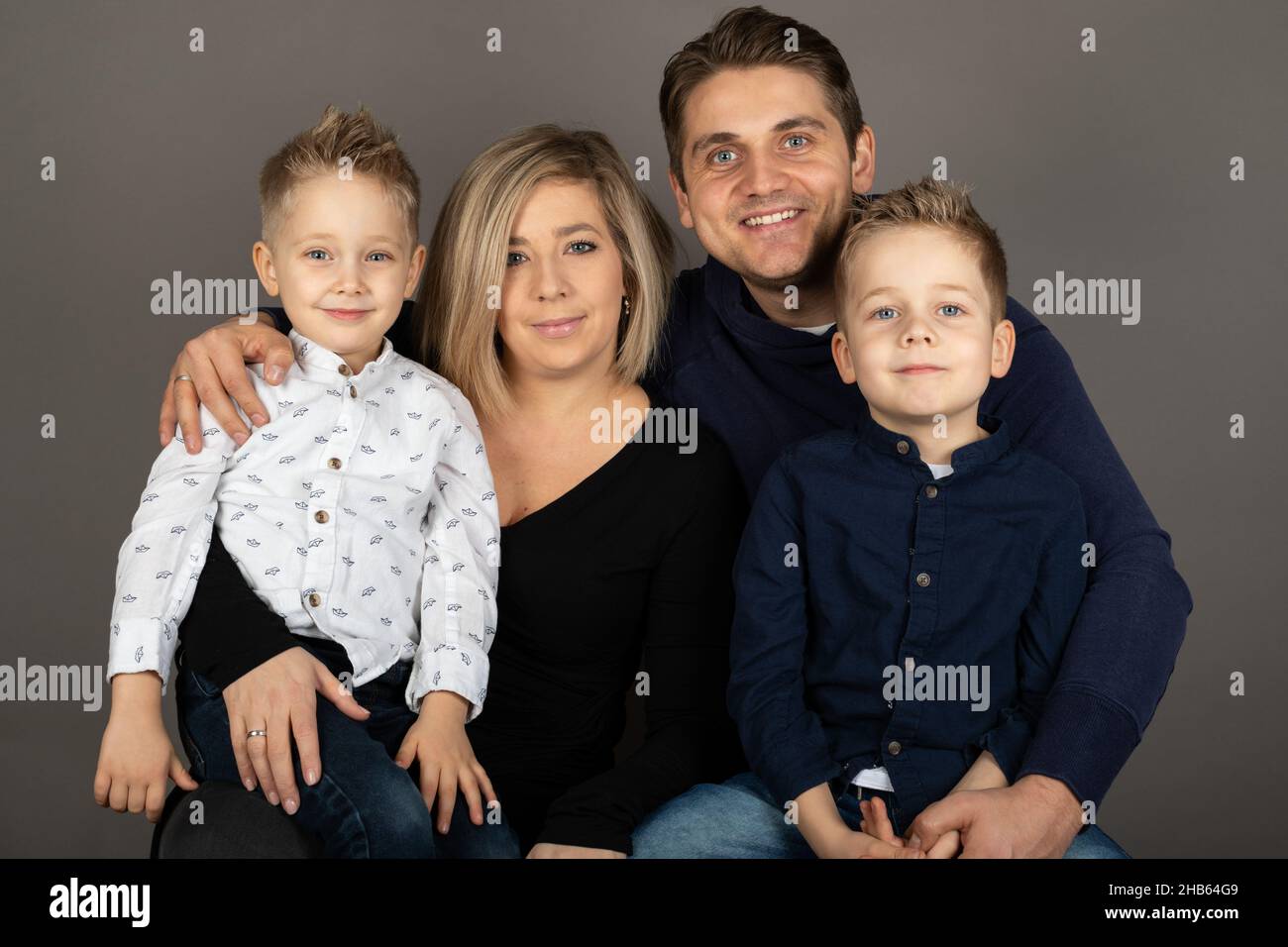 Portrait of a happy family looking to the camera in front of grey ...