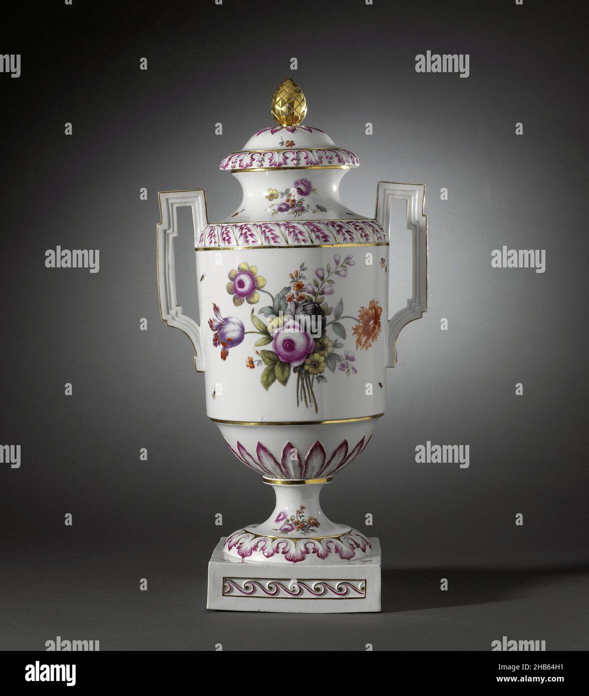 Covered vase with birds on a branch and bouquets, Lid vase of porcelain on a spreading foot ending in a square base and having a cylindrical body with rounded shoulder and narrowing to the foot. Spreading neck with a flat rim and high, angular ears. Painted on the glaze in blue, red, pink, green, yellow, purple, black and gold. On the belly two birds on a branch in a landscape and a bouquet of various flowers. In between are scattered flowers and insects. The narrowing part to the foot with a band of modeled raised leaf motifs in relief. The shoulder and foot with the same decoration as on the Stock Photo
