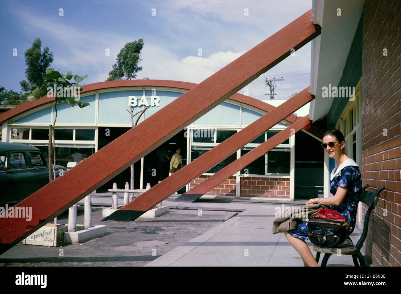 Woman sitting outside on bench outside cafe bar of petrol station near Sao Paulo, Brazil, 1962 Stock Photo