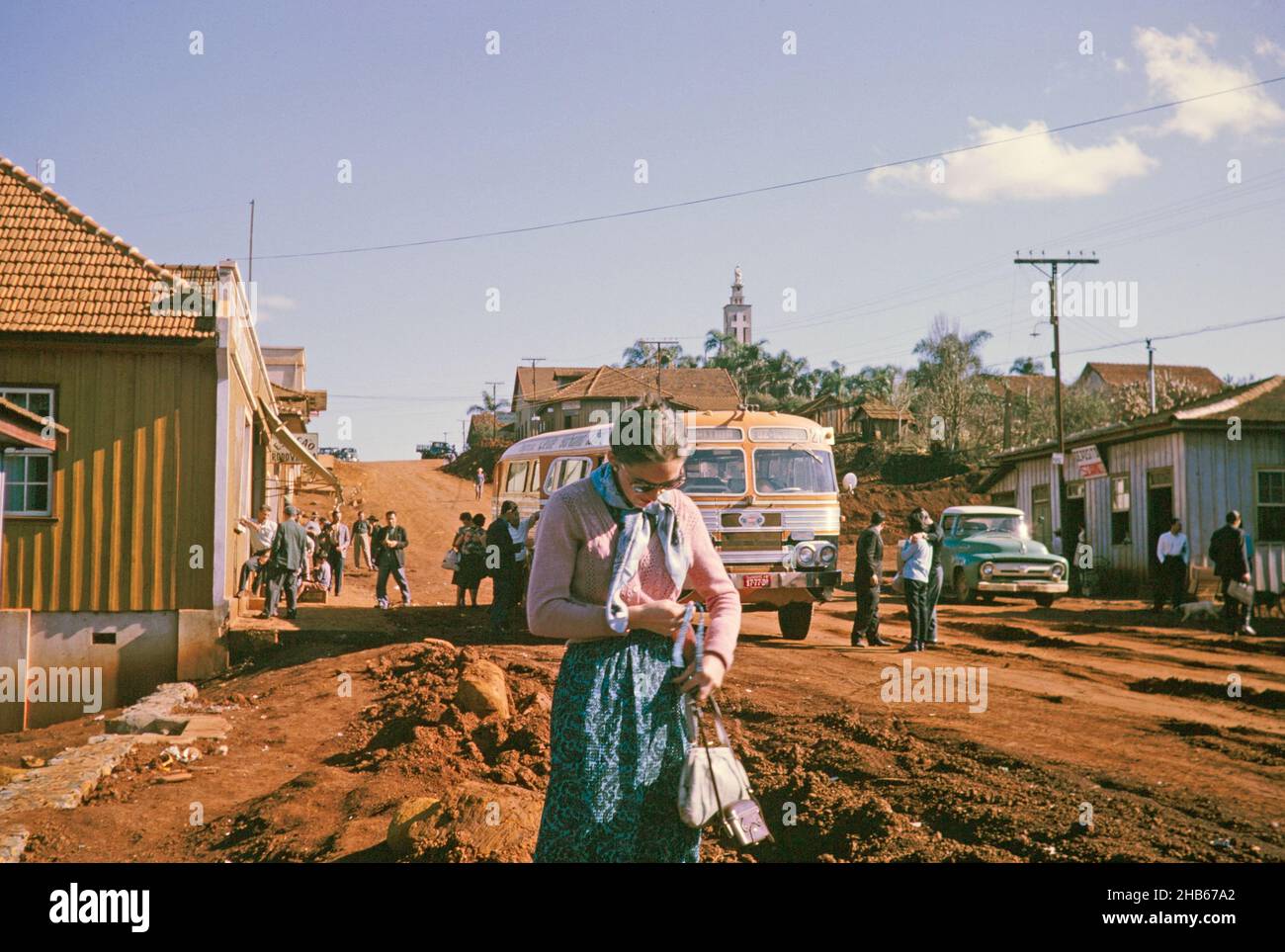 Bus stop in rural settlement on route between Curitiba and Foz do Iguaçu, Laranjeiras do Sol, Paraná state, Brazil in 1962, female tourist passenger in the foreground Stock Photo