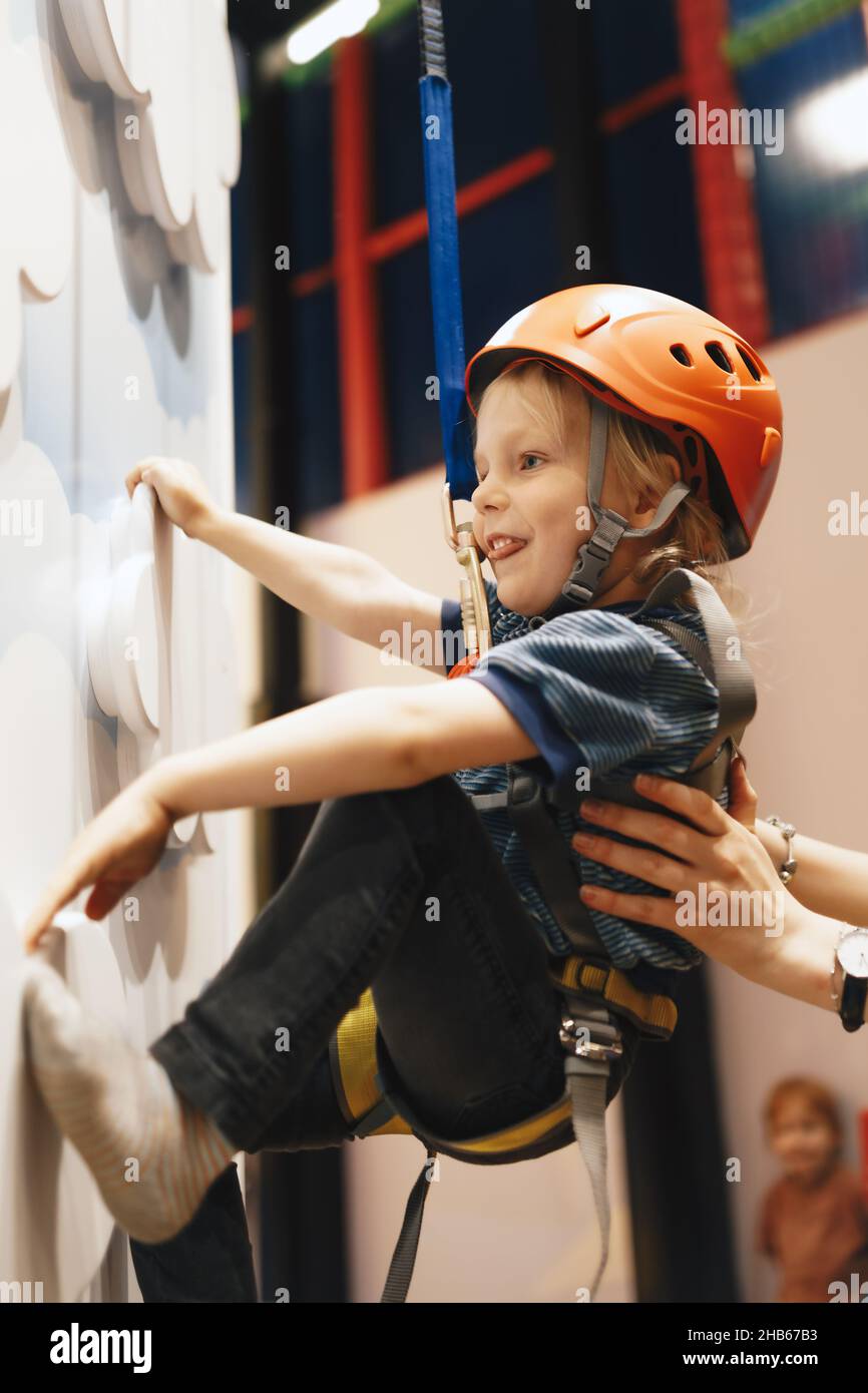 Mom and son at the climbing wall. Kids having fun at bouldering wall. Child learning at climbing class. Family sport, healthy lifestyle, happy family. Stock Photo