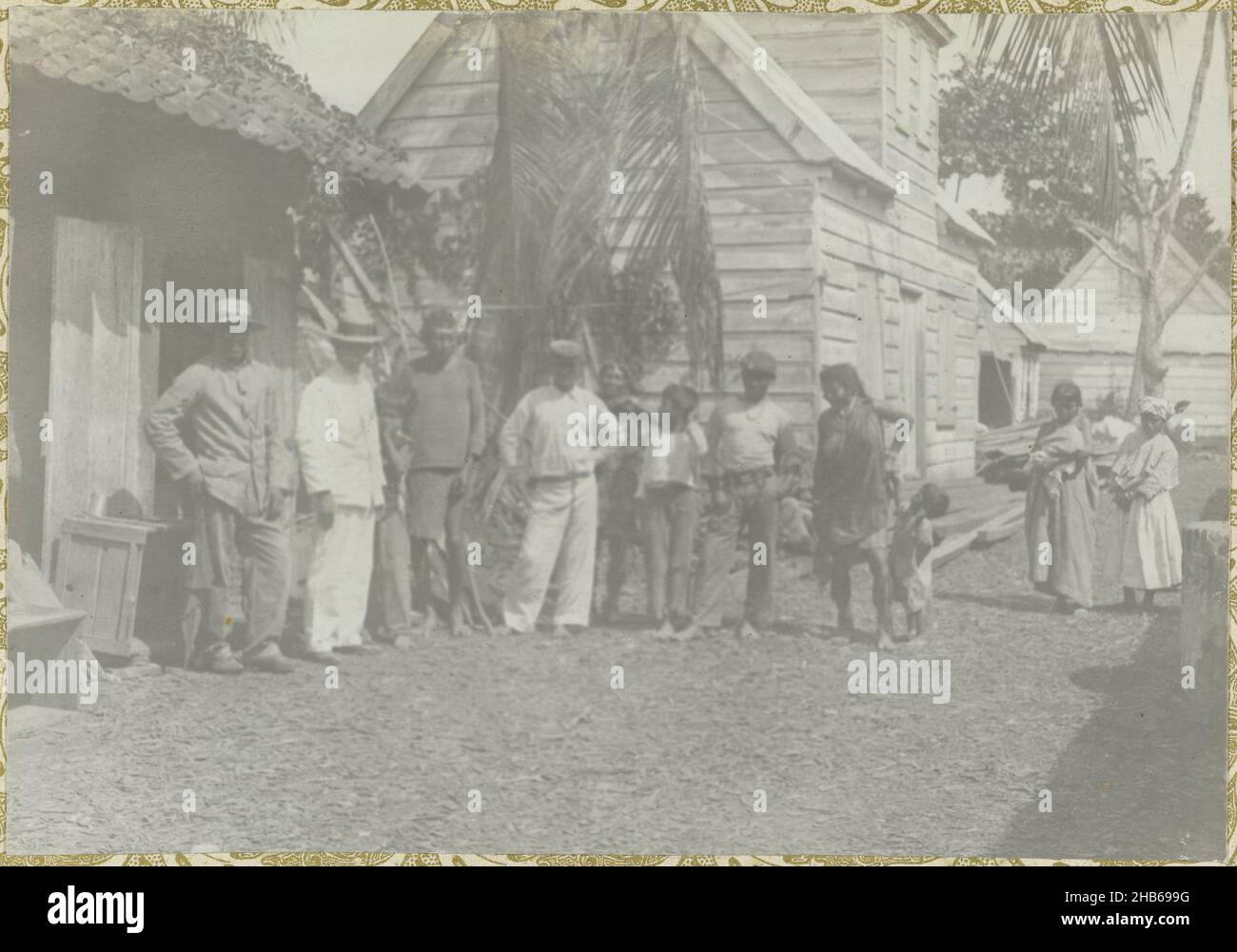 Villagers, A group of villagers standing in front of some houses. Part of the photo album Souvenir de Voyage (part 1), about the life of the Doijer family in and around the plantation Ma Retraite in Suriname in the years 1906-1913., Hendrik Doijer (attributed to), Suriname, 1906 - 1913, photographic support, gelatin silver print, height 115 mm × width 166 mm Stock Photo