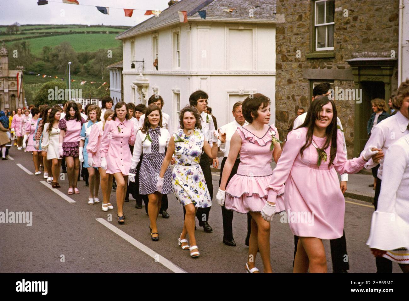 Couples walk hand in hand in procession for the Evening Dance, Flora Day, Helston, Cornwall, England, UK 1973 Stock Photo