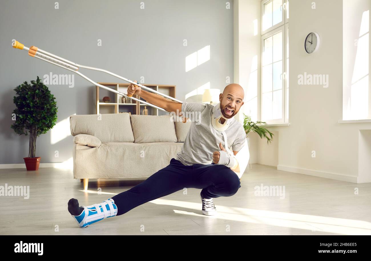 Happy man who's on sick leave due to his injuries is holding crutch and showing thumbs-up Stock Photo