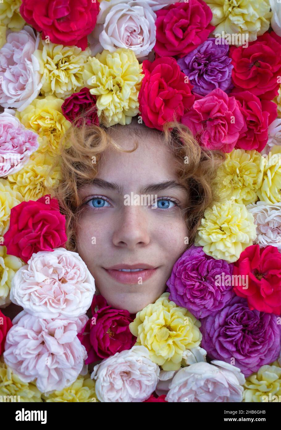 close-up face portrait of a beautiful young woman with many rose ...