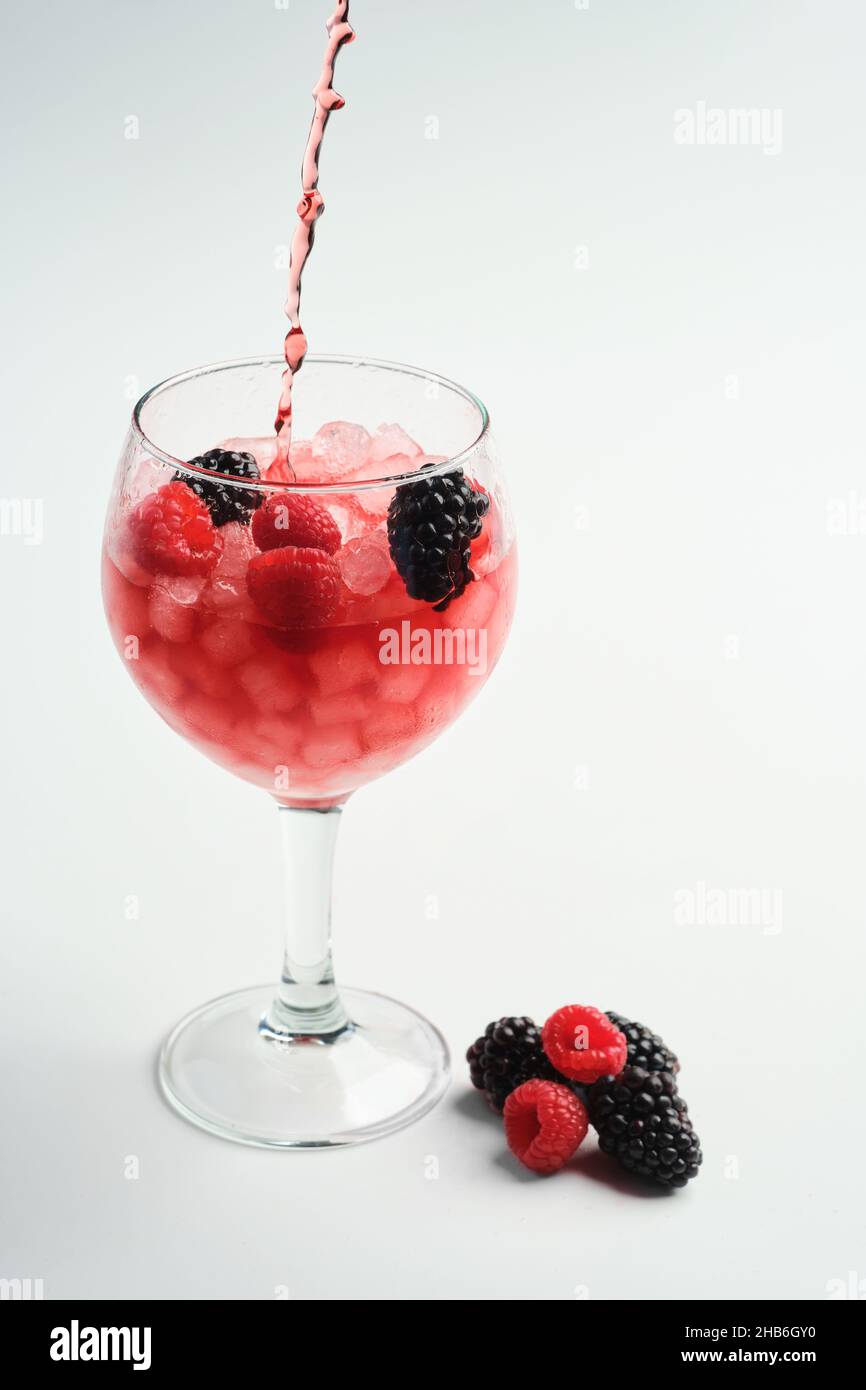 Pouring raspberry and blackberry gin into a full balloon glass with