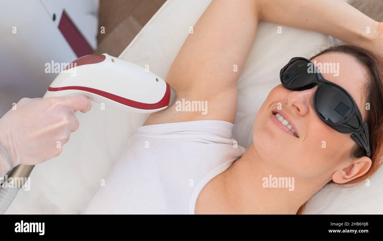 Doctor doing laser hair removal on a woman's armpit in the salon. An