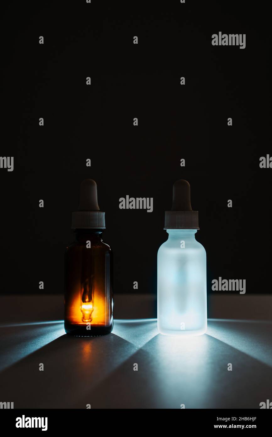 matte white and brown glass face serum bottles with droppers on dark background. Anti aging facial liquid with peptides and collagen Stock Photo