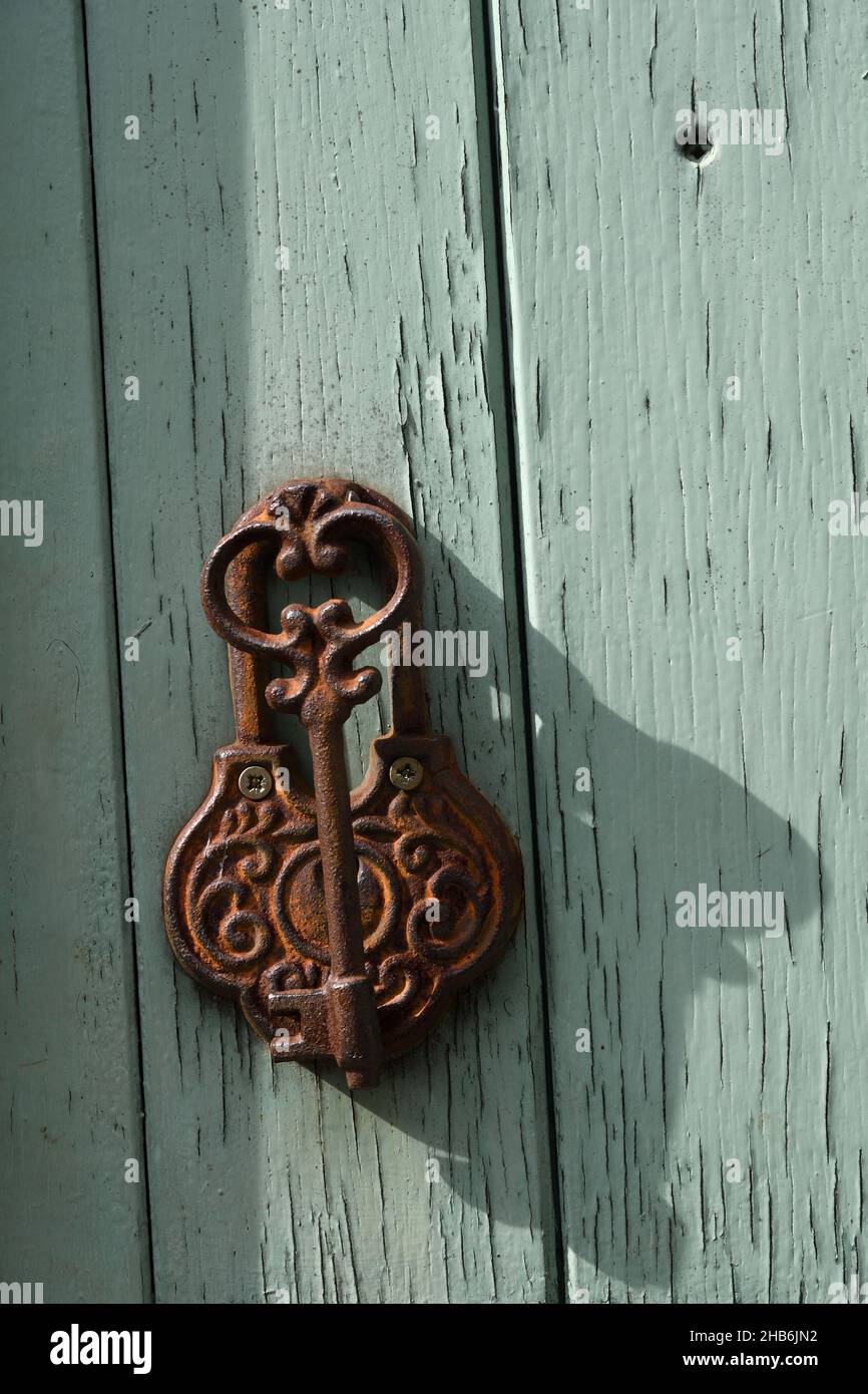 rusty old key as a door knocker at an old wooden door , France, Brittany, Departement Ille-et-Vilaine, Saint-Suliac Stock Photo