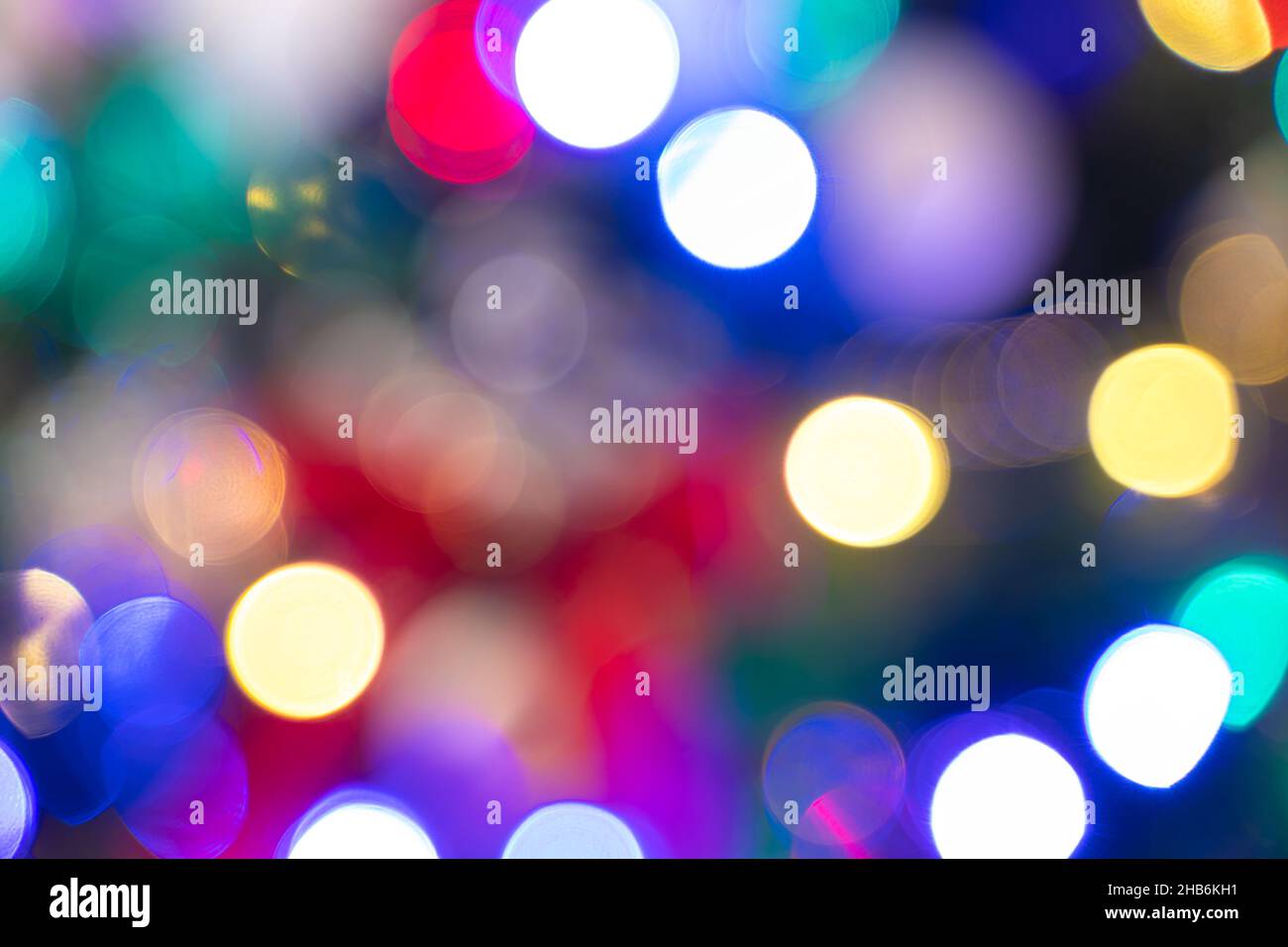 Defocused multicolored holiday lights. Christmas background with a festive Christmas tree with glowing garlands. Stock Photo