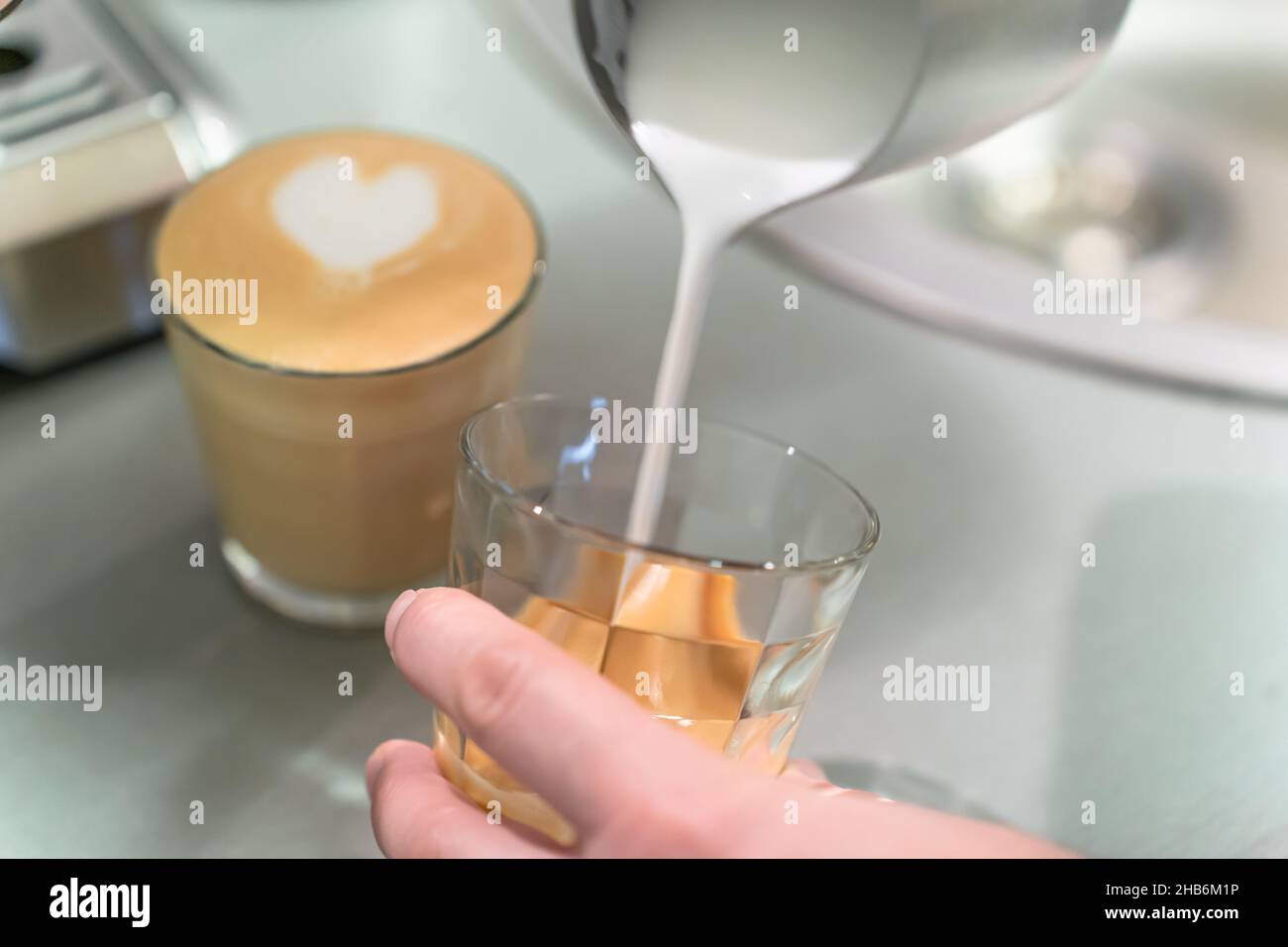 Barista pours whipped milk into a glass. Stock Photo