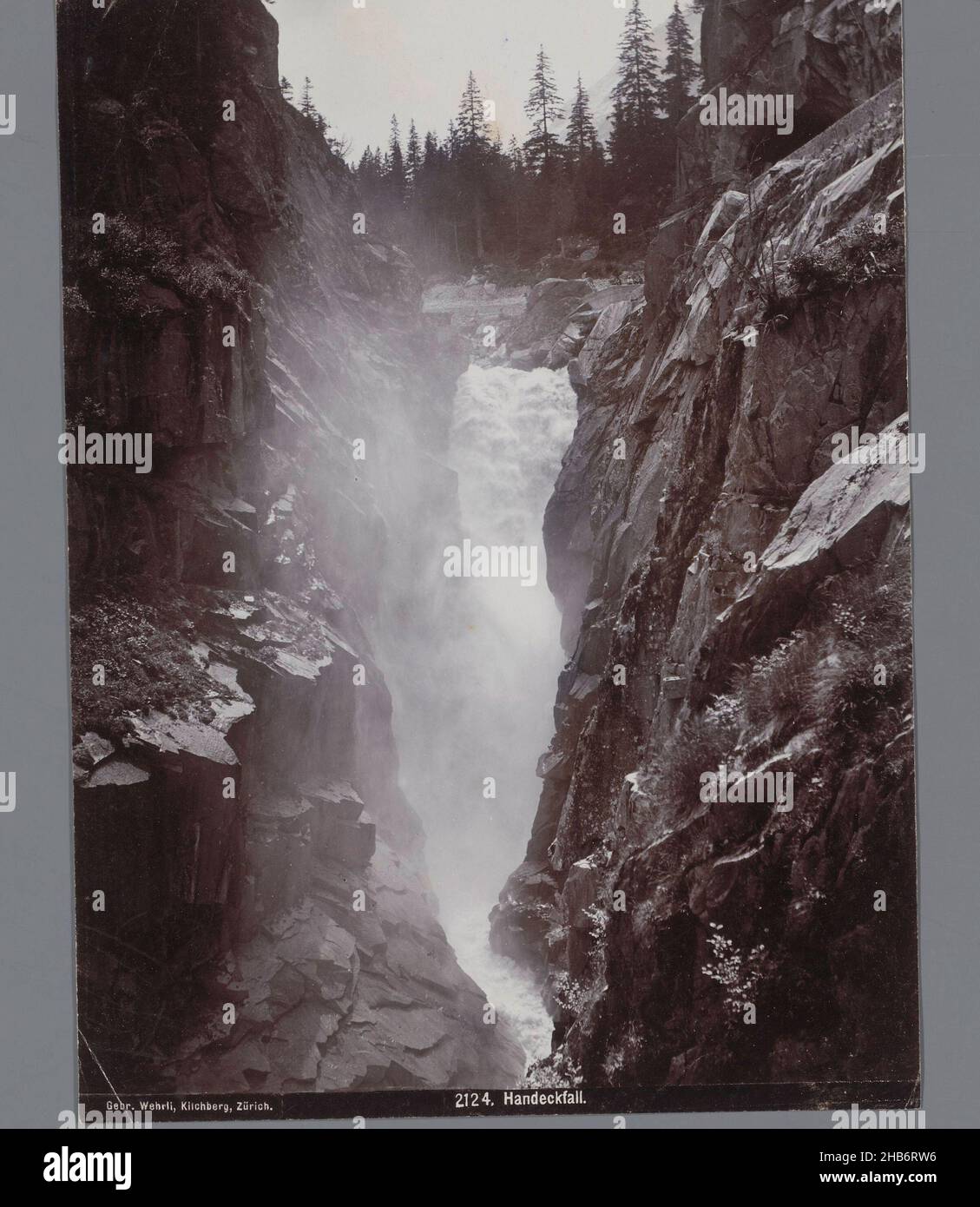 Waterfall the Handeckfall, Bernese Oberland, Switzerland, Mountain landscape cleaved by a waterfall, on the right and left steep rock faces and pine trees in the background., Gebrüder Wehrli, Switzerland, c. 1890 - c. 1920, paper, gelatin silver print, height 220 mm, width 165 mm Stock Photo